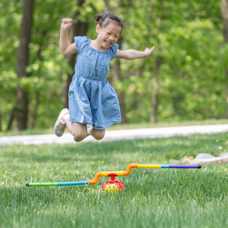 Child smiling and jumping over a 2-in-1 Musical Jump 'n Toss!