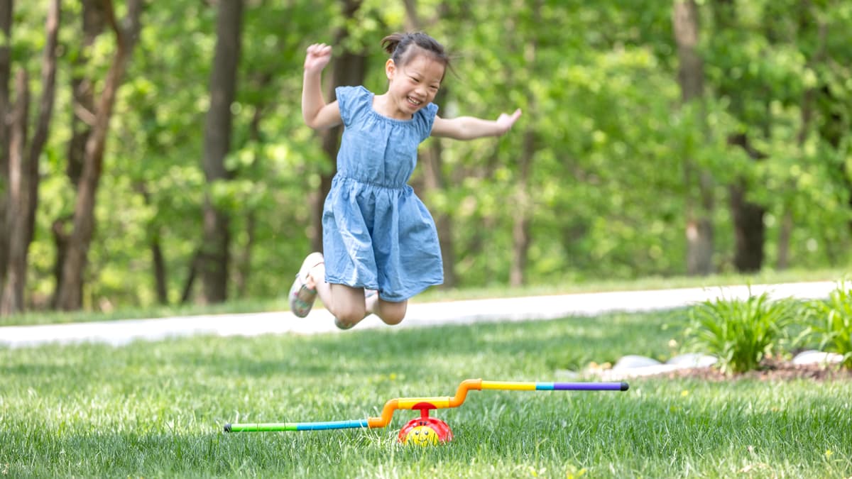 Child smiling and jumping over a 2-in-1 Musical Jump 'n Toss!