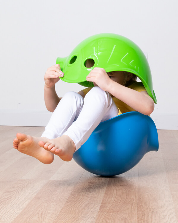 Child sitting in a blue bilibo and looking through a green bilibo!