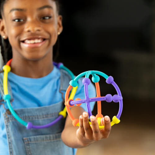 Child smiling while holding up and showing what they built with Plip Kit