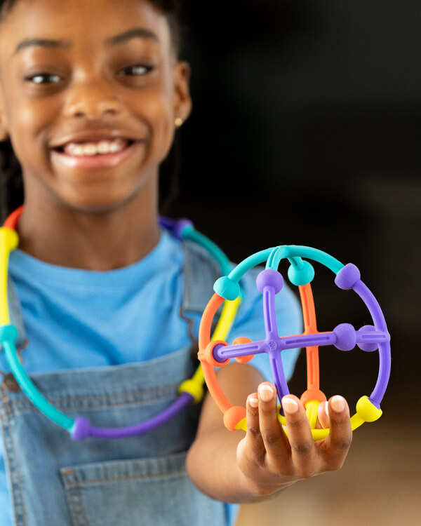 Child smiling while holding up and showing what they built with Plip Kit